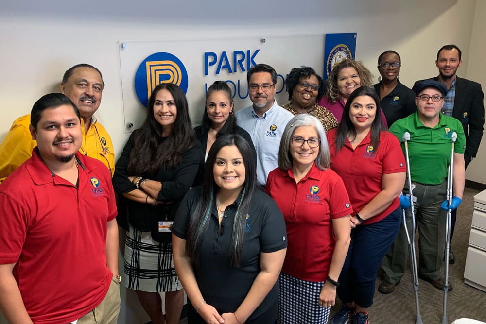 Park Houston staff posing for photo in front of logo at Park Houston office