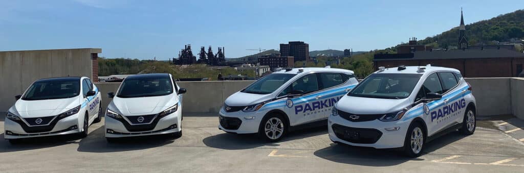 Three Nissan Leaf EVs, parked in front of a building, showcase the commitment of the Bethlehem Parking Authority to parking sustainability.